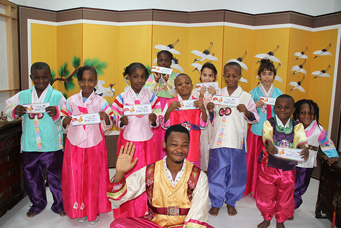 The Korean Cultural Centre in Nigeria hosts an event on Jan. 26 where people are able to experience a traditional Seollal Lunar New Year’s. The children hold up envelopes containing their <i>sebaetdon</i> New Year’s money (세뱃돈), a gift they received after performing a ceremonial <i>sebae</i> New Year’s bow (세배) to their elders.